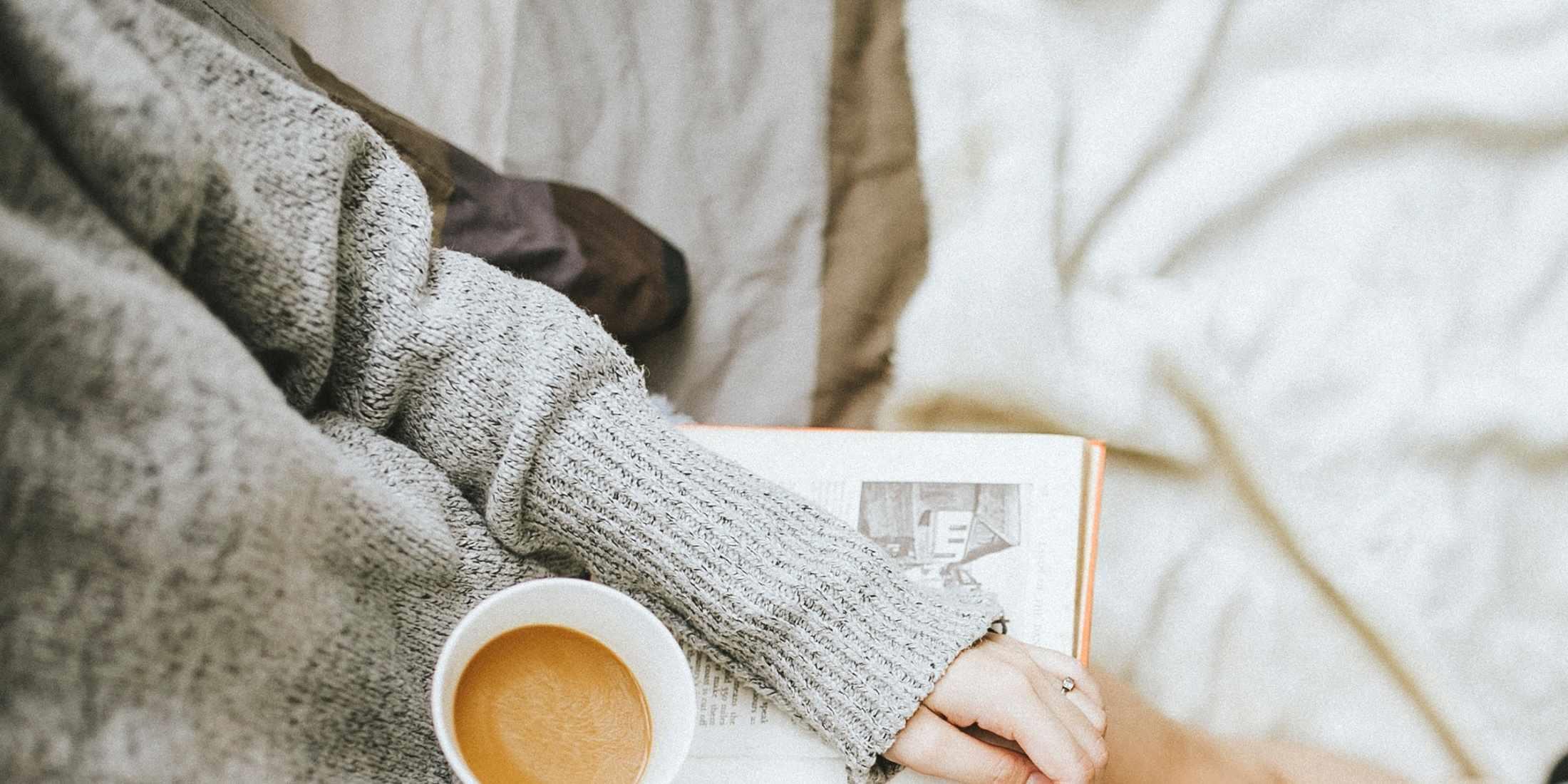 Woman cozy with a coffee and book on her lap